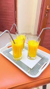 three glasses of orange juice on a tray on a table at Cozy 1 Bedroom Hall in Khor Fakkan