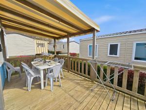 a patio with a table and chairs on a deck at Mobilhome in Litteau