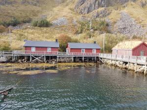 a dock with two red buildings on a body of water at Cottage from 1850 in Ballstad in Ballstad