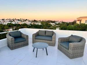 three chairs and a table on a balcony with a view at Villa Tara Christina in Carvoeiro