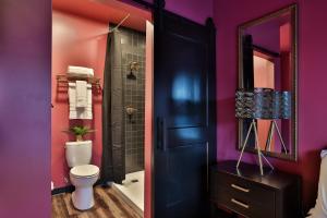 a bathroom with a toilet and a mirror and purple walls at Urban Collective Boutique Hotel in Edwardsville