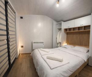 ein Schlafzimmer mit einem großen weißen Bett, auf dem zwei Handtücher liegen in der Unterkunft Tiny House Doi Frați in Drăguş