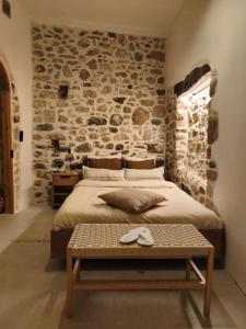 a bedroom with a large bed with a stone wall at ARETOUSA Private Village Suite in Sitia