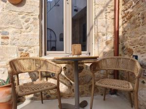 two wicker chairs and a table in front of a window at ARETOUSA Private Village Suite in Sitia
