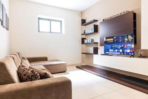 a living room with a couch and a flat screen tv at Mandalay Cozy & Affordable Apartment with Patio in Mellieħa