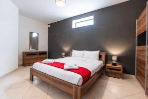 a bedroom with a large bed with a red blanket at Mandalay Cozy & Affordable Apartment with Patio in Mellieħa