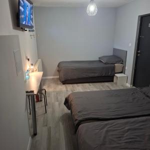 a room with two beds and a flat screen tv at FORT BLIZNE NOCLEGI - superior, standard & basic rooms in Blizne Łaszczyńskiego