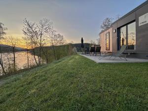 a house with a view of a lake and a table and chairs at Feriendorf Seeblick - Tiny Chalet Nr 8 in Neunburg vorm Wald