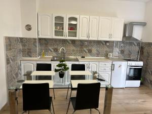 a kitchen with white cabinets and a table and chairs at Apartman Caminito in Zadar
