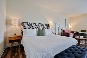 a bedroom with a bed with a blue ottoman and a table at Urban Collective Boutique Hotel in Edwardsville
