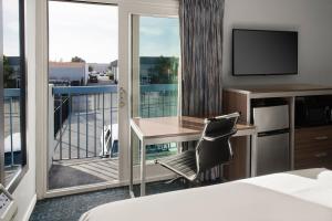 a hotel room with a balcony with a desk and a television at Sand Dollar Inn in Seaside