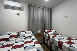 a bedroom with two beds and a window at Studio Sol in Mossoró