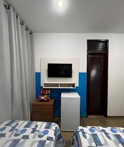 a bedroom with a bed and a tv on a wall at Studios Casamarela in Mossoró