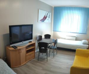 a living room with a television and a table with chairs at Noclegi Włocławek in Włocławek