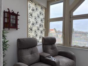 a living room with a chair and two windows at Ferienwohnung in Ballenstedt in Ballenstedt