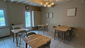 a room with tables and chairs and a clock on the wall at Le Chalet des Pins - La Forge De Clermont in Clermont