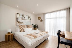 a white bedroom with a large bed and a desk at Super-Styled Light-Filled Eco Home in Torquay