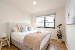 a white bedroom with a bed and a window at Super-Styled Light-Filled Eco Home in Torquay