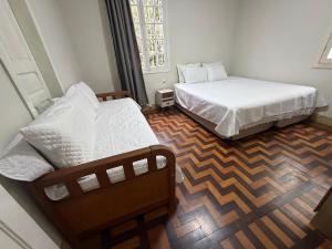 a bedroom with two beds and a wooden floor at Espaço do Imperador in Petrópolis