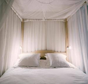a canopy bed with white sheets and pillows at Tripel B in Bruges