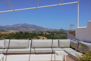 a couch on a balcony with mountains in the background at Beautiful villa with private pool and mountain views in Jimena de la Frontera