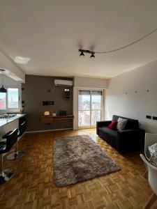 a living room with a black couch and a kitchen at Espacio San Martin - Departamento en plena peatonal con Seguridad 24 hs in Santa Fe
