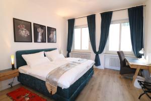 a bedroom with a bed and a desk and windows at Altstadt Suites am Kamp, Parkhaus möglich in Paderborn