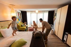 Ein Mann und ein Kind stehen auf einem Bett in einem Zimmer. in der Unterkunft iVAVev Is'us in Eforie Sud + 222 Fotos