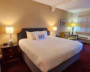 a bedroom with a large white bed and a chair at Bavarian Inn in Shepherdstown