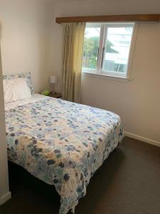 a bedroom with a bed with a floral bedspread and a window at Rest & Relax Holiday Home in Whangarei