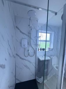 a white bathroom with a shower and a sink at Bide A While at the Port in Portrush +13 photos