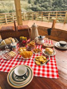 a picnic table with food on a red and white checked table cloth at Chalé Rio Capetinga 01 in Anchieta