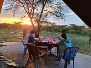 two people sitting at a table watching the sunset at Oloirien camps in Maasai Mara National Reserve