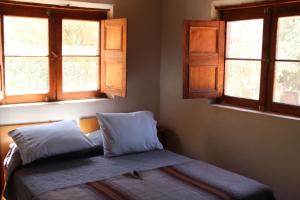 a bed with two pillows in a room with windows at Casa Garces in San Pedro de Atacama