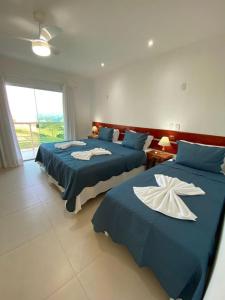 a bedroom with two beds with blue and white sheets at Pousada No Alto da Serra Conservatória in Conservatória +25 photos