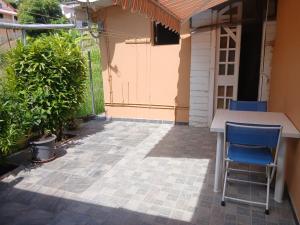 a patio with a table and chairs in front of a house at Chez Myky in Sainte-Marie