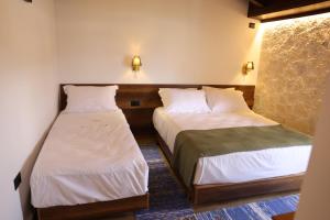 two beds in a room with white sheets at Hotel Panorama in Berat
