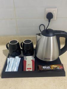 a tray with a tea pot and two mugs at شـقـة بغـرفـتـيـن Two rooms in Al Kharj