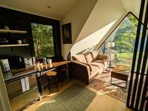 a living room with a couch and a kitchen with a large window at Bison Farm - Cabin "Cielo" in Culpeper