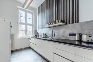 a kitchen with white cabinets and a sink and a window at Fürstlich Wohnen am Circus mit Blick zur Granitz in Putbus