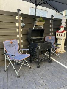 two chairs and a grill on a patio with an umbrella at Riverside-Appartements in Boppard