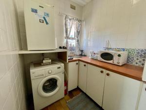 a kitchen with a washing machine and a microwave at Beachfront Studio Flat in Cape Town