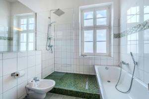a bathroom with a tub and a toilet and a sink at Fürstlich Wohnen am Circus mit Blick zur Granitz in Putbus