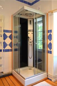 a glass shower in a bathroom with blue and white tiles at Chambres d'Hôtes Launay Guibert in Miniac-Morvan