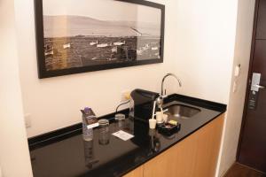 a bathroom counter with a sink and a picture on the wall at Dazzler by Wyndham Lima Miraflores in Lima