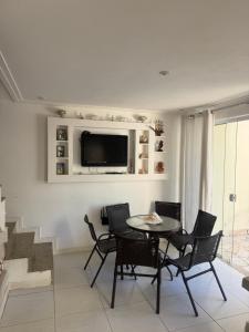 a living room with a table and chairs and a tv at Casa condomínio Praia do Jardim in Angra dos Reis