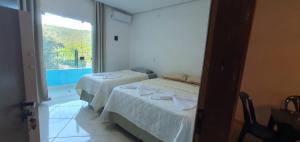 two beds in a room with a window at Hospedaria Mandassaia in Lençóis +9 photos