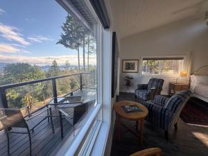 a room with a balcony with a bed and chairs at Salt Spring Sunrise in Saltspring Island