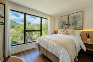 a bedroom with a large bed and large windows at apartamento em Itaipava novo, Granja Brasil Resort in Petrópolis +134 photos