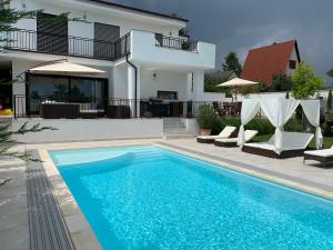 a swimming pool in front of a house at Theodora Residence in Balatonalmádi